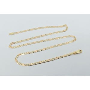 May include: A gold-colored chain necklace with a mariner link design. The chain is displayed on a light gray background. The necklace has a lobster claw clasp.