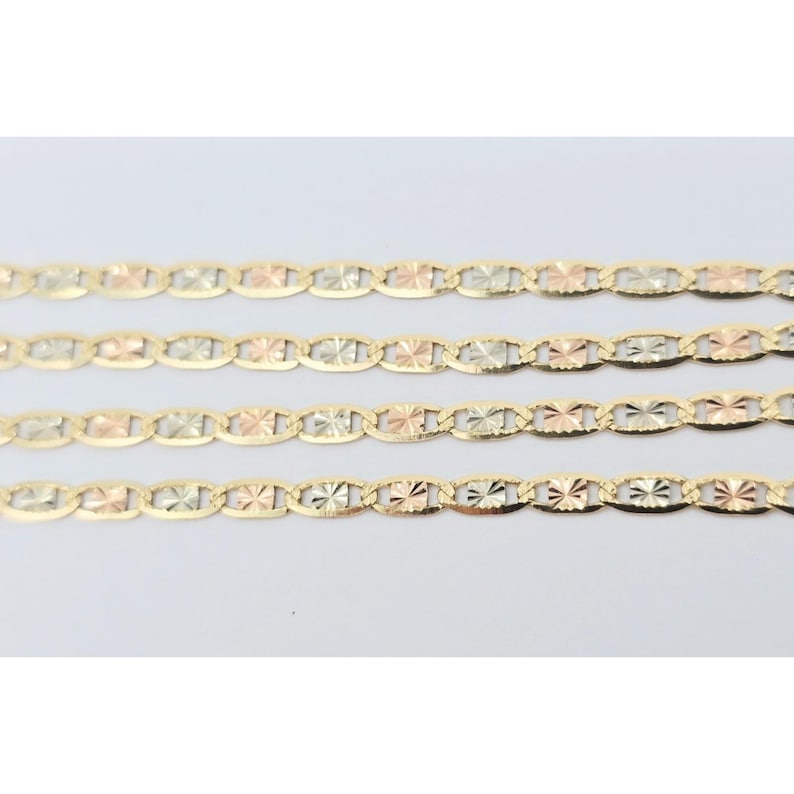 May include: Four gold-toned chains with a repeating oval and starburst design. Each link alternates between yellow, rose, and white gold. The chains are displayed against a white background.
