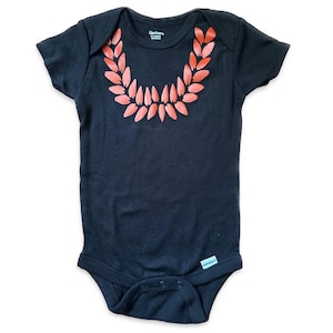 May include: A black baby onesie with a red leaf garland design on the front. The onesie has short sleeves and snaps at the bottom.