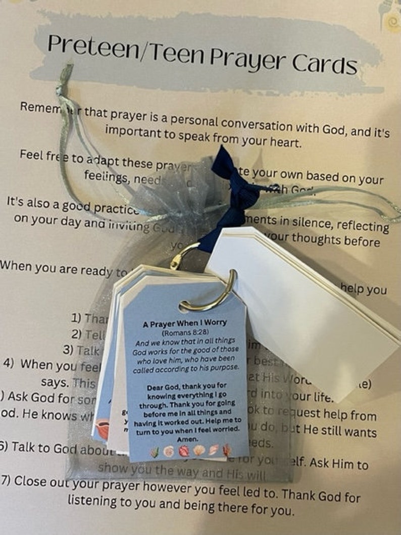 May include: A set of prayer cards for preteens and teens. The cards are decorated with a light blue ribbon and have a white background with black text. The text on the cards includes a prayer for when you worry, and steps for praying.
