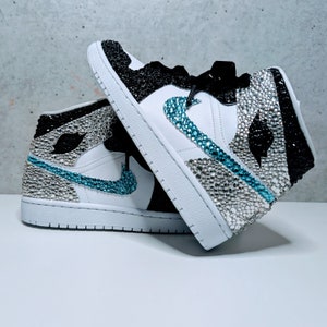 May include: A pair of white high-top sneakers with black and turquoise accents. The sneakers are covered in rhinestones.