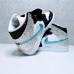 May include: White and black high-top sneakers with a turquoise swoosh and rhinestones covering the entire shoe.