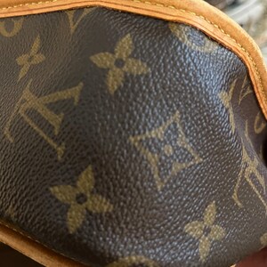 May include: Close-up of a brown leather handbag with the iconic repeating floral and logo pattern. The bag features a light brown trim and stitching, showcasing a classic design.