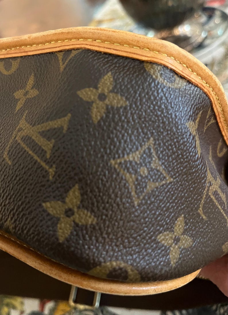 May include: Close-up of a brown leather handbag with the iconic repeating floral and logo pattern. The bag features a light brown trim and stitching, showcasing a classic design.