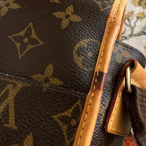 May include: Close-up of a brown leather handbag with the iconic monogram pattern. The bag features a light brown leather trim and a dark brown strap. The stitching is visible along the edges, and the hardware is gold-toned.