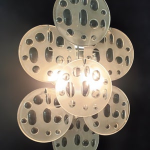 May include: A modern, white, glass pendant light fixture with a cluster of round, textured, frosted glass shades. The shades have a pattern of small, round holes.