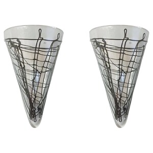 May include: Pair of clear glass cone-shaped wall sconces with black wire designs.