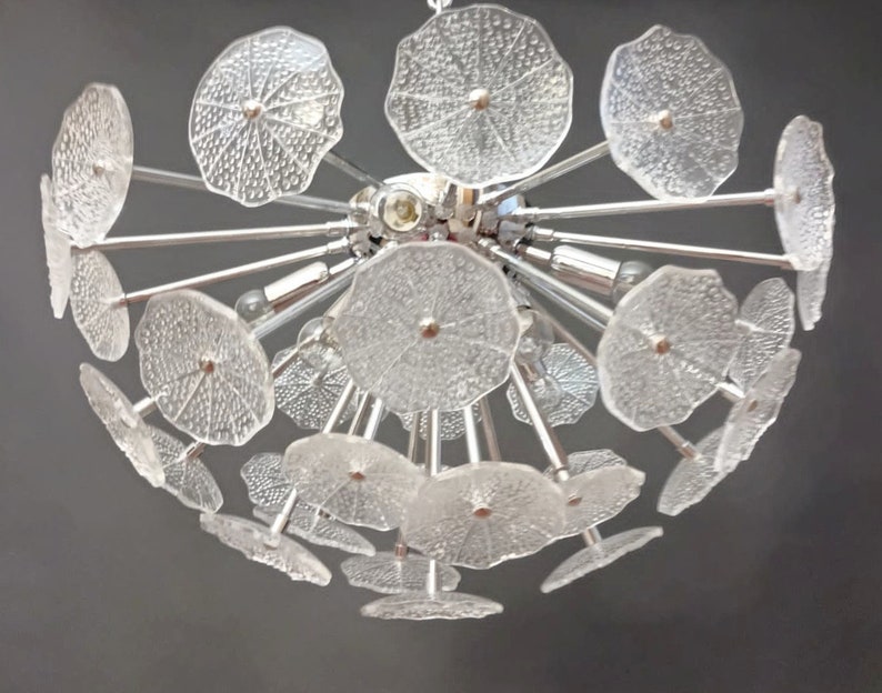 May include: A chrome and glass chandelier with multiple clear glass flower-shaped shades. The chandelier has a modern design and is perfect for a contemporary home.
