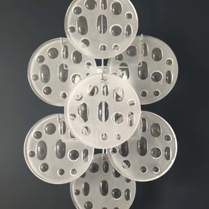 May include: A set of seven white, round, frosted glass discs with various sized holes. The discs are suspended from a metal chain.