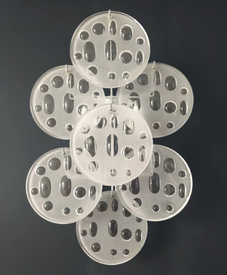 May include: A set of seven white, round, frosted glass discs with various sized holes. The discs are suspended from a metal chain.