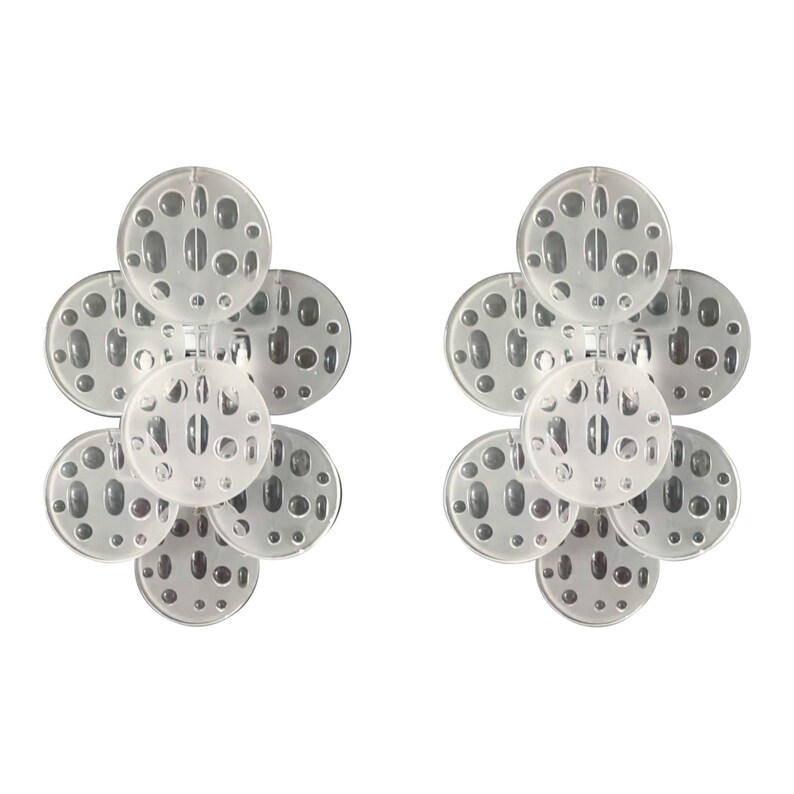 May include: A pair of clear acrylic earrings with a flower-like design. Each earring is made up of five overlapping circles with a textured surface.