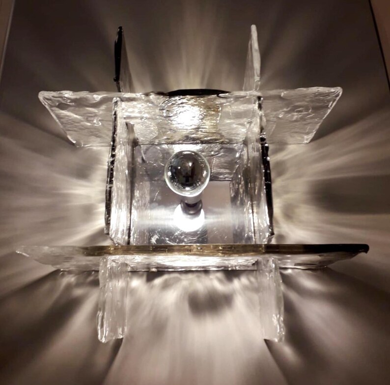 May include: A clear glass light fixture with a square shape and a frosted finish. The light fixture has a single light bulb in the centre.