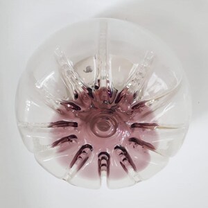 Pu&ograve; includere: Una bottiglia di vetro trasparente con un fondo viola. La bottiglia ha un design a stella ed &egrave; perfetta per un vaso o un pezzo decorativo.
