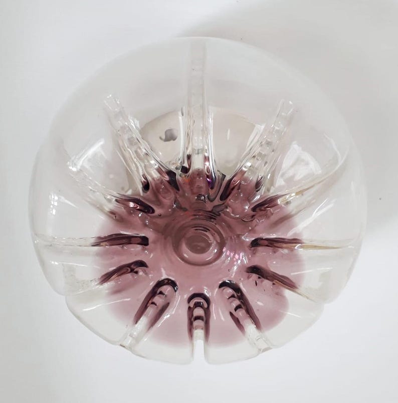 Pu&ograve; includere: Una bottiglia di vetro trasparente con un fondo viola. La bottiglia ha un design a stella ed &egrave; perfetta per un vaso o un pezzo decorativo.