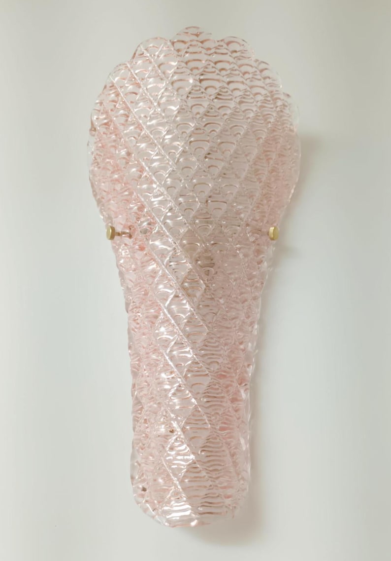 May include: A pink glass wall sconce with a textured diamond pattern. The sconce has a rounded top and a pointed bottom.