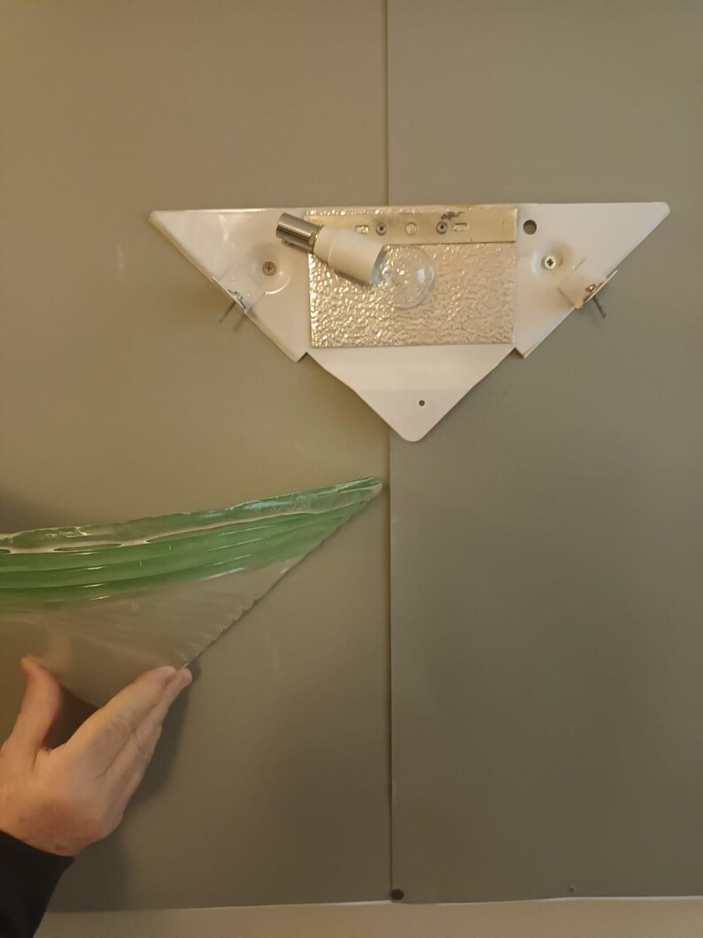 May include: A white triangular light fixture with a light bulb and a green glass shade.