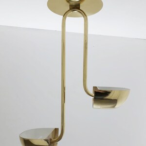 May include: A brass ceiling light fitting with two curved shades. The fitting has a simple, modern design.