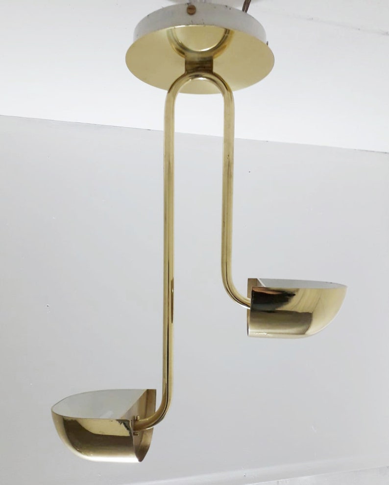 May include: A brass ceiling light fitting with two curved shades. The fitting has a simple, modern design.