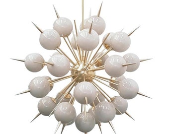 May include: A gold-toned chandelier with a starburst design. The chandelier has multiple white glass globes with sharp points extending from each globe.