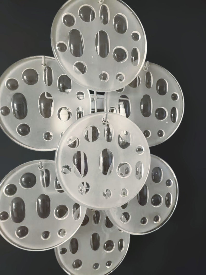 May include: A white frosted glass pendant light fixture with multiple circular discs, each with a pattern of small and large holes. The discs are connected by metal rods.