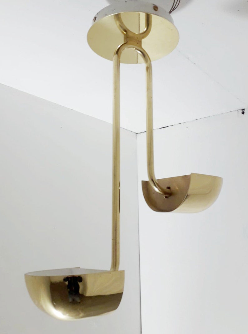 May include: A brass pendant light fixture with two curved shades. The fixture has a simple, modern design.
