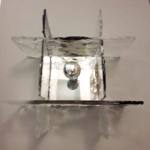 May include: A mirrored glass lampshade with a silver orb in the centre. The lampshade is made of multiple pieces of glass that are joined together to create a geometric design.