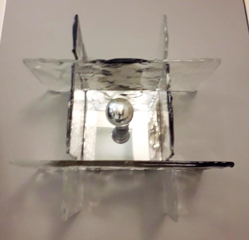 May include: A mirrored glass lampshade with a silver orb in the centre. The lampshade is made of multiple pieces of glass that are joined together to create a geometric design.
