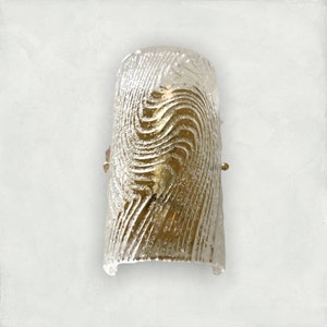May include: A gold-toned wall sconce with a clear glass shade featuring a swirling, textured pattern.