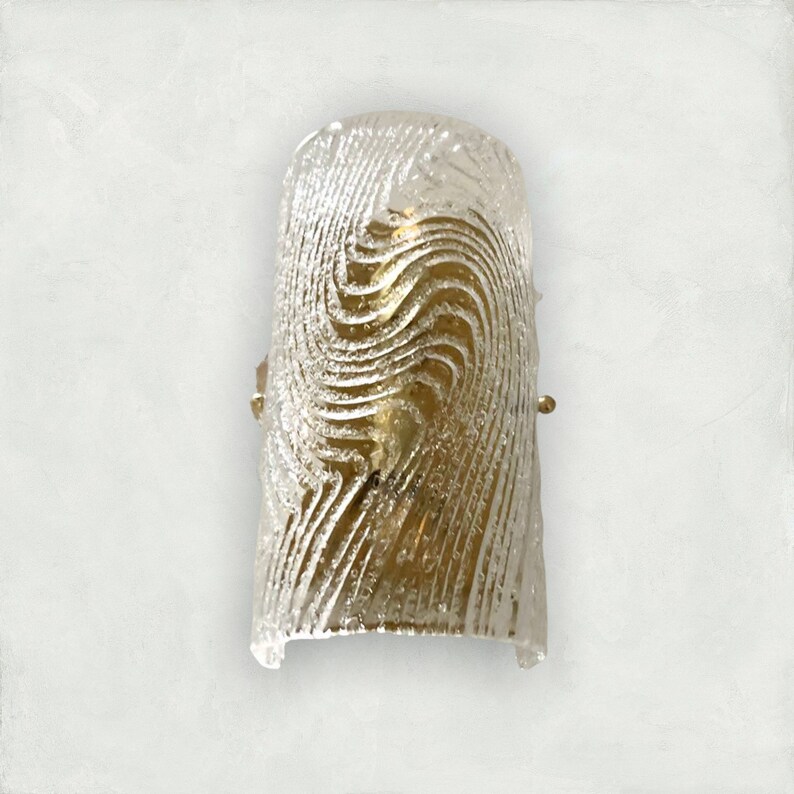 May include: A gold-toned wall sconce with a clear glass shade featuring a swirling, textured pattern.