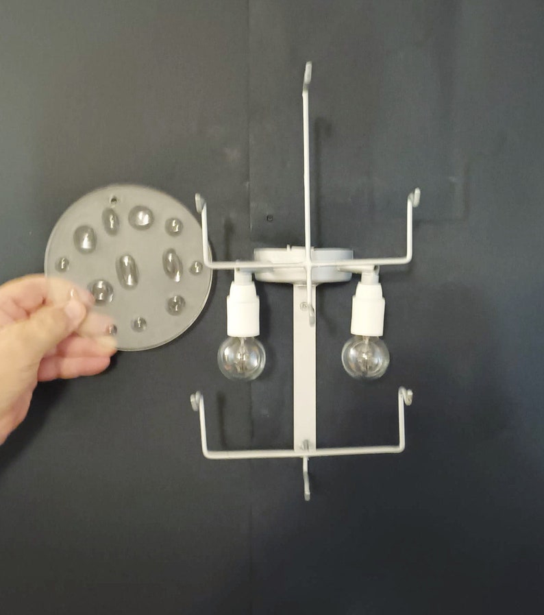 May include: White metal light fixture with two clear light bulbs and a round, clear plastic diffuser with multiple small holes.
