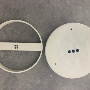 May include: Two white plastic ceiling light fixture parts. One part is a round ring with a crossbar and four small holes. The other part is a round disc with three holes.