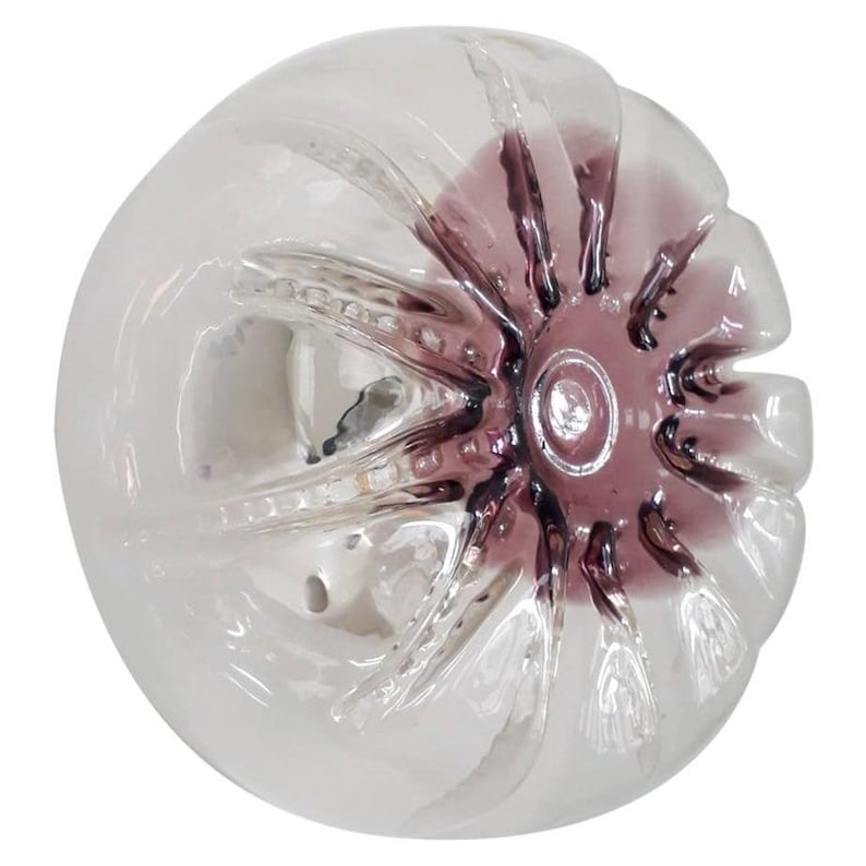 Pu&ograve; includere: Un tappo per bottiglia in vetro trasparente con una superficie testurizzata e un design a forma di stella di colore viola.