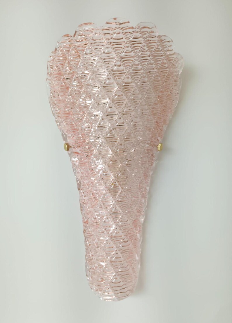 May include: A pink glass wall sconce with a textured, diamond-shaped pattern. The sconce has a gold metal mounting bracket.