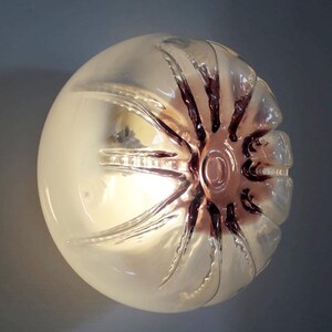 Pu&ograve; includere: Un globo di vetro trasparente con un motivo a stella testurizzato in una tonalit&agrave; viola scuro. Il globo &egrave; illuminato dall'interno, creando un bagliore morbido.