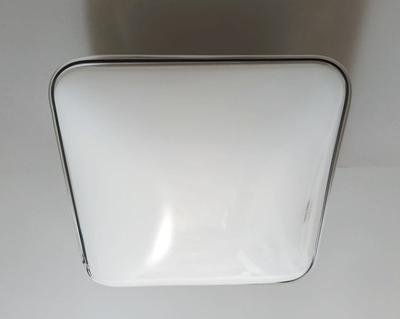 May include: A white square ceiling light fixture with a silver trim.