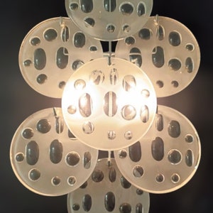 May include: A white ceiling light fixture with multiple round, frosted glass shades. Each shade has a pattern of small, round holes.