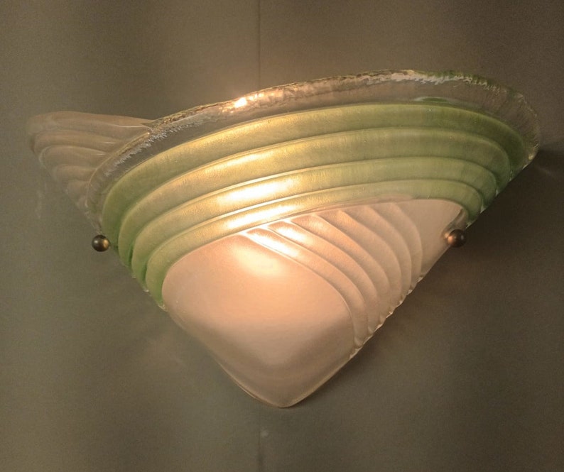 May include: A white and green glass wall sconce with a frosted glass shade and a decorative design.