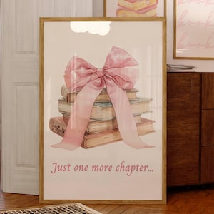 May include: A framed print featuring a watercolour illustration of a stack of books tied with a pink ribbon. The text "Just one more chapter..." is printed below the books.