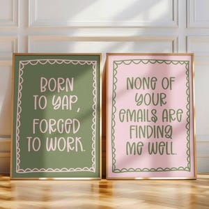May include: Two framed art prints with gold frames and decorative borders. One print is green with the text "BORN TO YAP, FORGED TO WORK." The other is pink with the text "NONE OF YOUR EMAILS ARE FINDING ME WELL."