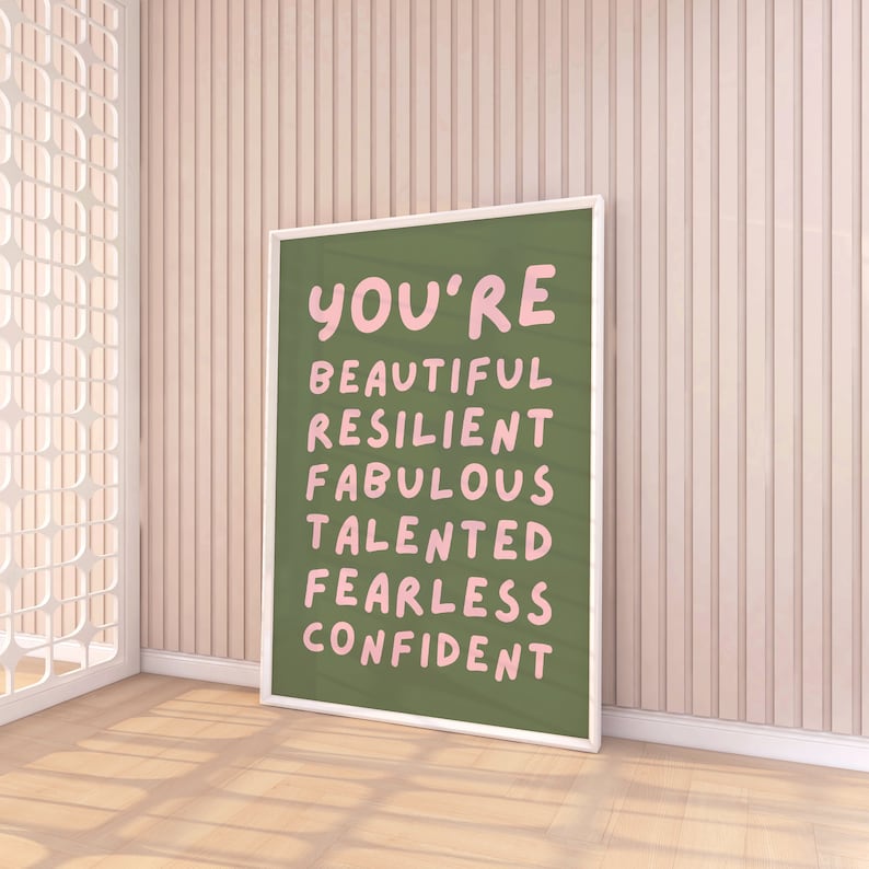 Op de afbeelding: Een ingelijst groene poster met witte letters die "You're Beautiful Resilient Fabulous Talented Fearless Confident" zeggen.