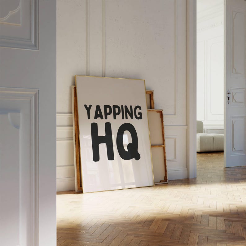 May include: A white framed poster with the text "YAPPING HQ" in black lettering.