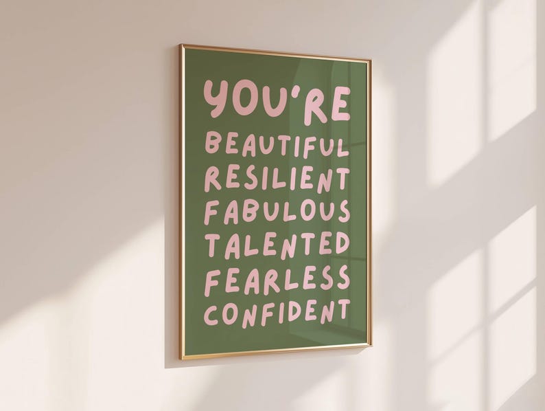 Op de afbeelding: Een groene poster met een lijst, met de tekst "You're" in roze, gevolgd door de woorden "Beautiful, Resilient, Fabulous, Talented, Fearless, Confident" in roze.