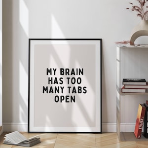May include: A black framed print with a white background and black text that reads "My brain has too many tabs open".