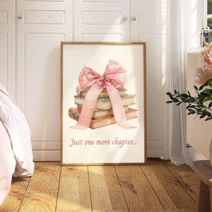 May include: A framed print featuring a watercolour illustration of a stack of books tied with a pink ribbon. The text "Just one more chapter..." is printed below the illustration.