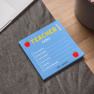 May include: A blue Teacher Notes notepad with a red apple graphic and a pencil illustration. The notepad includes checkboxes for tasks like calling parents and grading papers. The text "Mrs. James" is printed at the bottom.