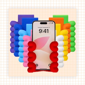 May include: A smartphone with a screen displaying the time 9:41 and the date Tuesday, September 12, held by a red plastic stand shaped like a hand with four fingers. Behind it are several other hand-shaped stands in purple, blue, pink, white, yellow, orange, and green.