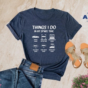 May include: A heather navy blue t-shirt with the text "Things I do in my spare time" and a list of car-related activities, including "Drive Cars", "Take Care of My Car", "Research Cars", "Talk About Cars", "Think About Cars", and "Dream About Cars".