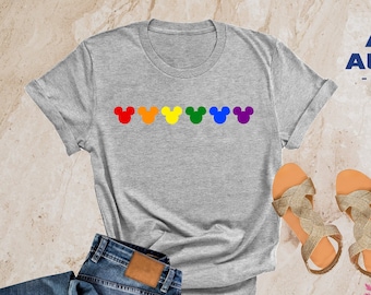 Op de afbeelding: Heather lichtgrijs T-shirt met een rij regenboogkleurige Mickey Mouse-koppen.