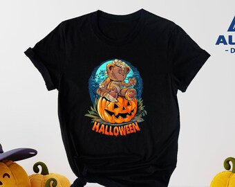 May include: Black t-shirt with a graphic of a teddy bear sitting on a jack-o'-lantern. The text "HALLOWEEN" is printed below the image. The t-shirt is from Alpine Design.