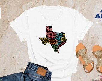 May include: White t-shirt with a black outline of the state of Texas filled with colorful text that says "Panhandle, Plain, Big Bend,  Coy Hill,  South,  West,  Central,  East,  and more."